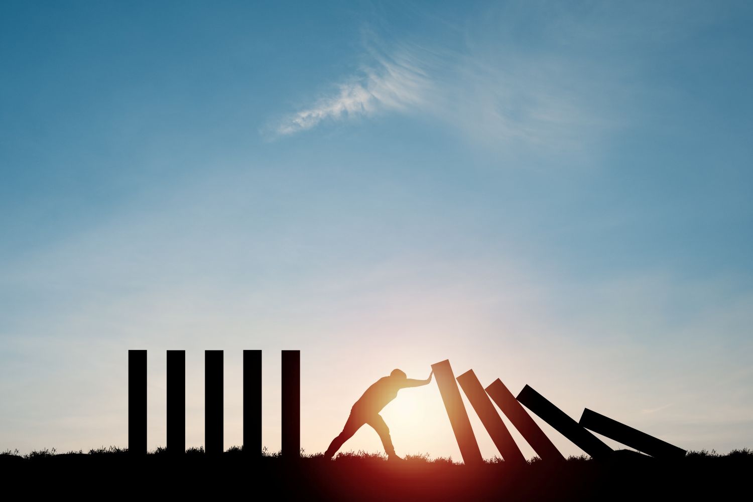 Picture of a man holding back the domino effect in his life. Ginny Estupinian PhD program teaches how to recover from failure stopping the frustration